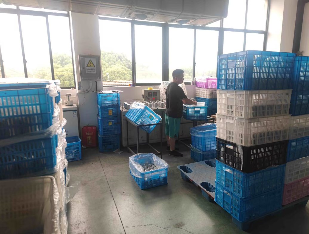 Vacuum flask insulation testing station at Jupeng Drinkware factory in Yongkang — operator checking semi-finished stainless steel bodies for vacuum loss
